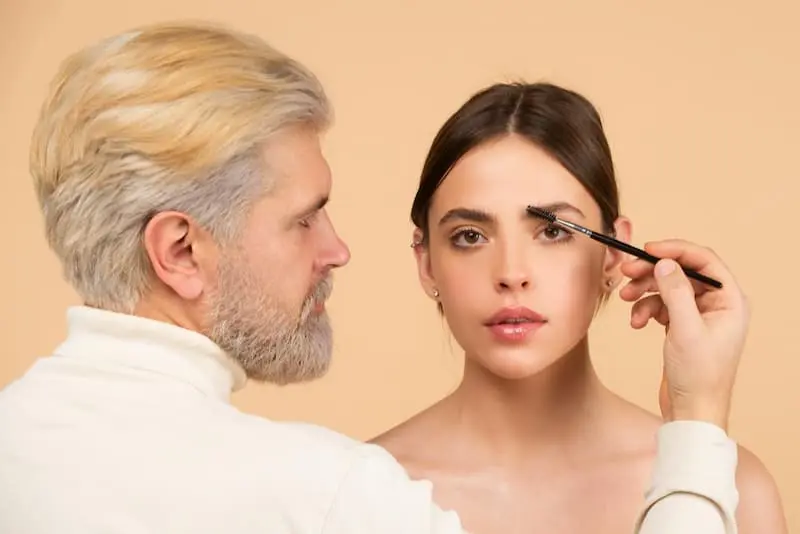 A man doing Microbladed eyebrows on client